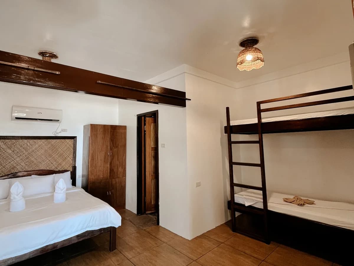 Beachfront Bungalow interior with white bedding, wooden bunk beds and a woven pendant light.