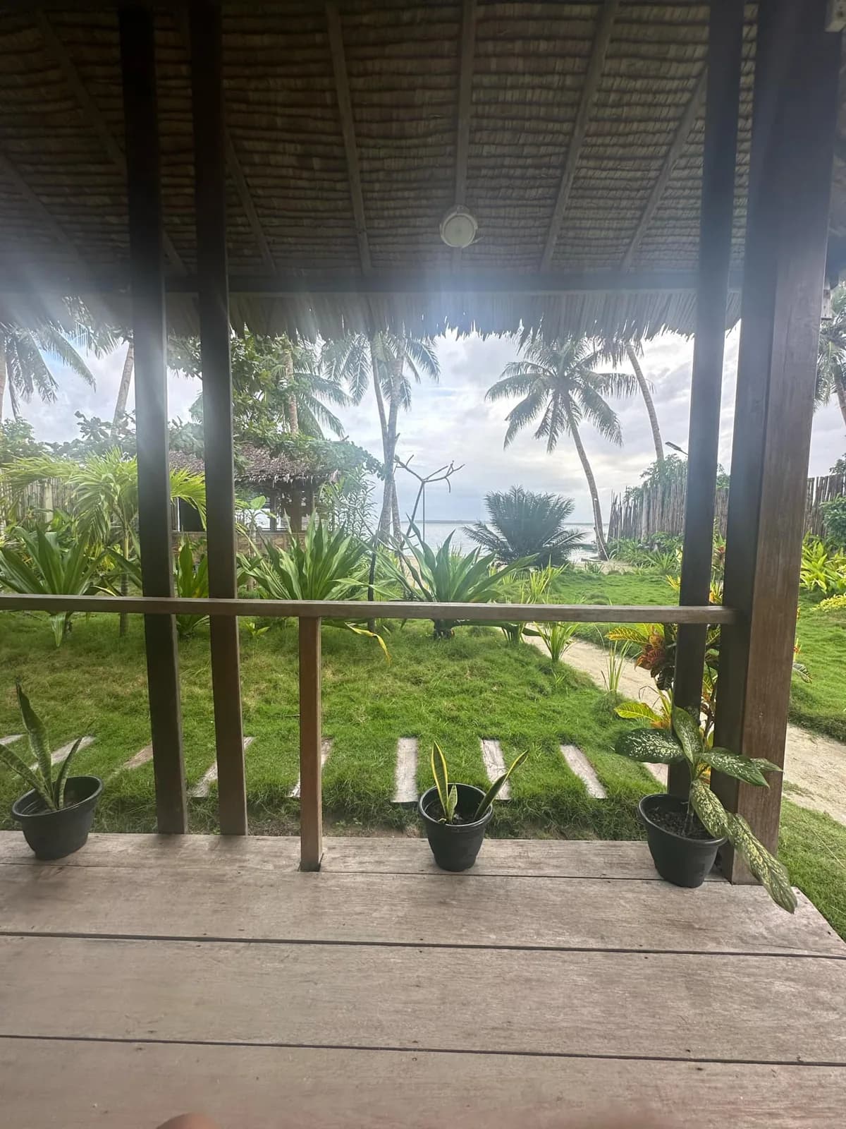 View from the Beachfront Bungalow terrace across tropical greenery toward the sea.
